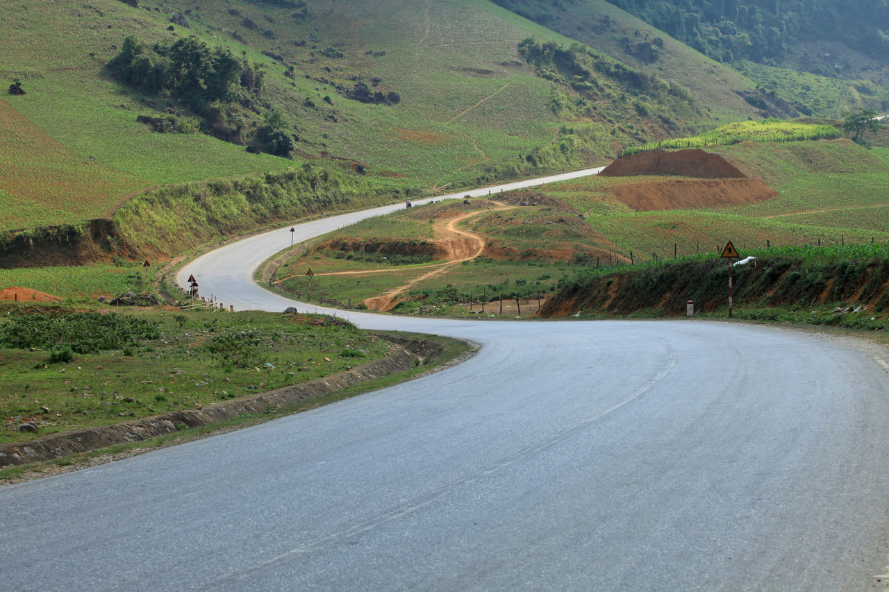Highway without traffic through hills and mountains during summer on a sunny day